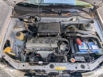 un moteur de voiture dont le capot est ouvert, garé dans la rue