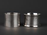 two silver cups on a black surface with a dark background