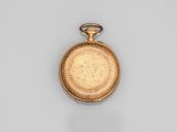 une vieille montre de poche en or avec une chaîne, posée sur une surface blanche