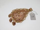 une photo d'une broche en or à laquelle est attachée une étiquette