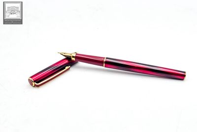 the pen is red with gold trim and has a gold tip