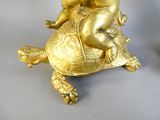 une figurine en or représentant un bébé assis sur une tortue