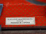 a red suitcase with a label on it that says magasin despenants passage de lopera