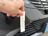 a person holding a piece of paper on the front of a car