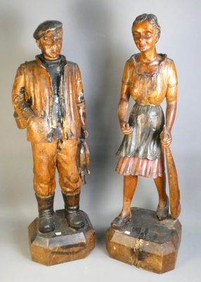 deux statues en bois représentant un homme et une femme debout l'un à côté de l'autre