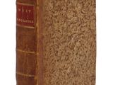 un vieux livre à la couverture brune posé sur une surface blanche