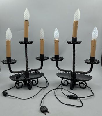 une paire de bougeoirs en métal et en verre noir, avec des bougies blanches dépolies