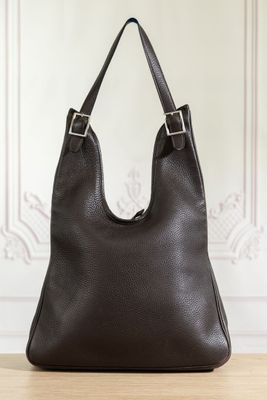 a black leather handbag sitting on top of a wooden table