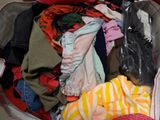 a suitcase full of clothes and clothes sitting on the floor