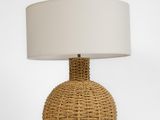 a rattan table lamp with a white shade on top of it