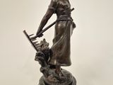 statue en bronze représentant une femme avec un panier et un chien, posée sur un socle en marbre