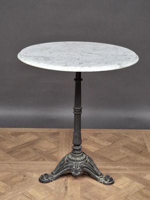 une table au plateau en marbre blanc posée sur un parquet