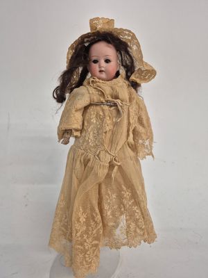 an old fashioned doll with a hat and dress on a white surface