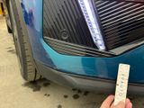 a person holding a remote control in front of a blue car