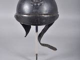 un casque orné d'un crâne, posé sur un socle