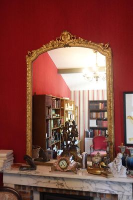 un miroir posé sur une cheminée dans une pièce aux murs rouges