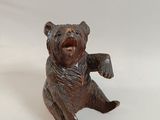 a small bronze bear figurine sitting on a white surface