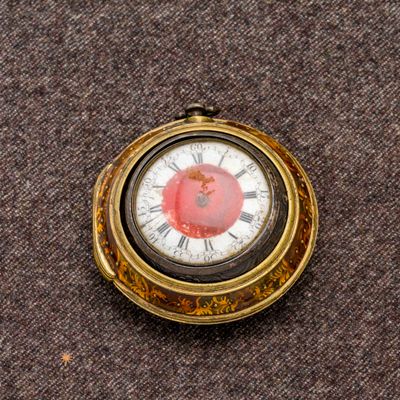 une montre de poche en or avec un cadran rouge