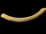 a close up of a gold bracelet on a black background