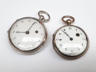 deux montres de poche en argent posées côte à côte sur une surface blanche