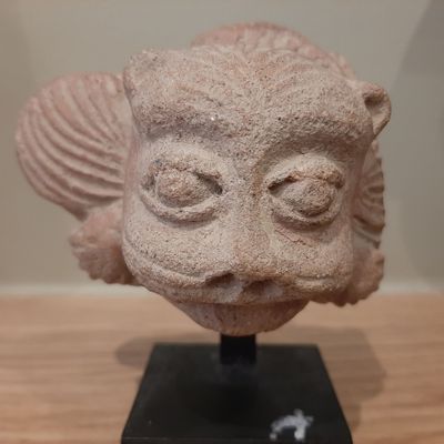 a stone sculpture of a fish on a black stand