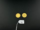 a close up of two gold coins and a tag on a black surface
