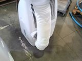 a white air conditioner sitting on the floor next to a box