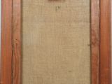 an old wooden picture frame with a piece of fabric hanging on the wall