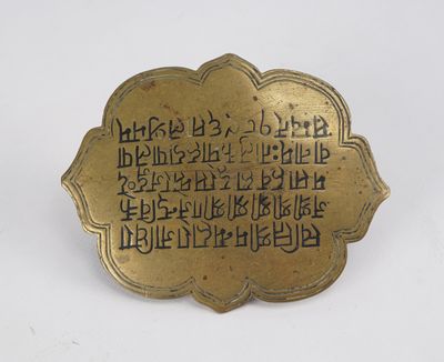 une assiette en or portant une inscription, posée sur une surface blanche