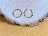 pair of silver wedding rings sitting on top of a piece of wood
