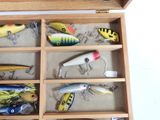 many different types of fishing lures in a wooden box