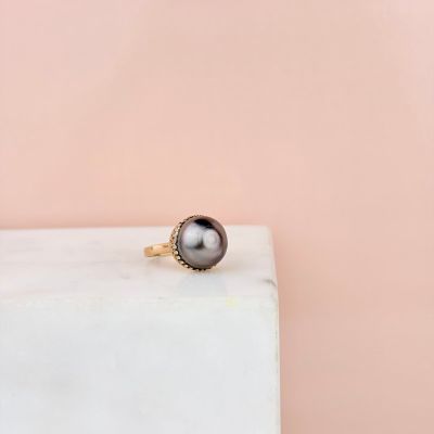 a black pearl ring sitting on top of a white marble block