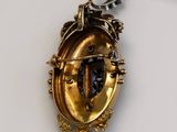 a gold locke with a black stone in it on a red string