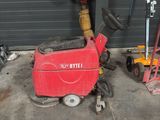 a red machine sitting in a garage next to other tools