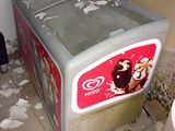 un petit réfrigérateur qui se trouve dans un coin de la pièce