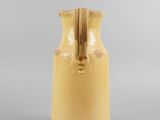 a yellow vase with a wooden handle on a gray surface