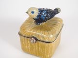 a small blue bird sitting on top of a yellow box