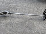 a pole saw on the ground next to a car