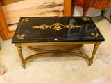 une table basse noire et dorée, ornée de motifs dorés