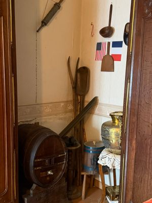 une porte qui mène à une pièce où sont accrochés tout un tas d'objets au mur