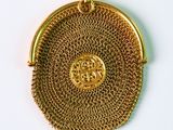 un gros plan d'un porte-monnaie doré posé sur une surface blanche