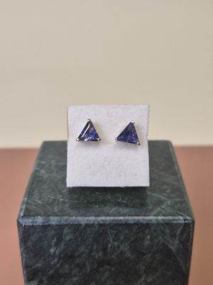 a pair of triangle shaped blue sapphire earrings on top of a marble block