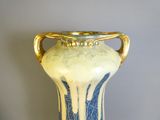 un vase bleu et blanc muni d'une anse dorée, posé sur une table