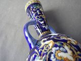 a blue and gold vase with a handle on a table