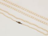 a close up of a necklace with pearls on a white surface