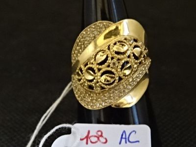 une bague en or posée sur une bouteille de vin à laquelle est accrochée une étiquette de prix