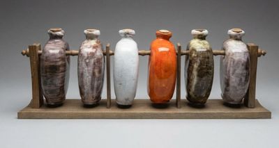 cinq vases posés sur un socle en bois, sur un fond gris