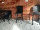 tables and chairs in a room with a brick wall in the background