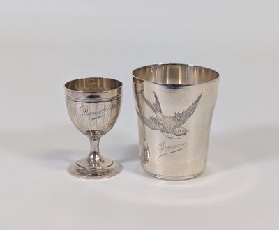 une coupe en argent et un gobelet en argent posés sur une table
