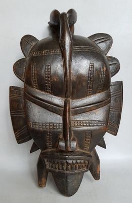 une image d'un masque en bois accroché au mur